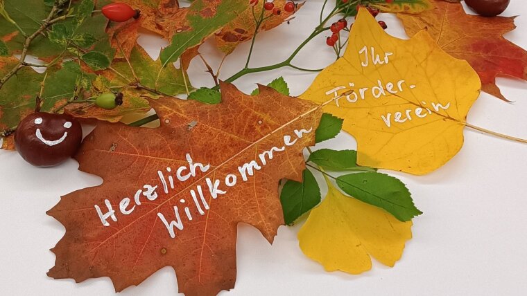 Herbstlaub auf Tisch beschrieben mit "Herzlich willkommen - Ihr Förderverein"