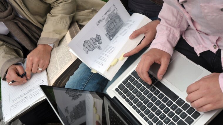 Studierende mit Laptop und Büchern.